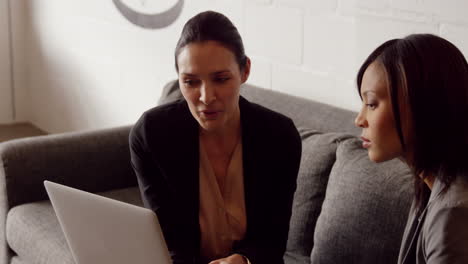 Serious-businesswomen-discussing-while-looking-on-laptop