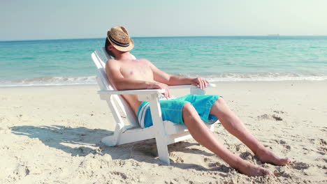 Man-relaxing-on-deck-chair-at-the-beach
