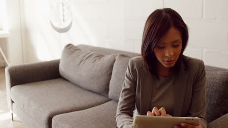 Smiling-businesswoman-using-her-tablet-on-the-couch