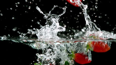 Strawberries-falling-in-water-on-black-background