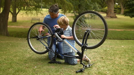 Padre-Y-Su-Hijo-Arreglando-Una-Bicicleta-En-El-Parque