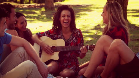 Amigos-Felices-En-El-Parque-Haciendo-Picnic-Y-Tocando-La-Guitarra.