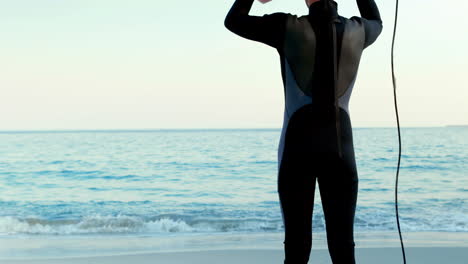 Man-in-wetsuit-with-a-surfboard-on-a-sunny-day