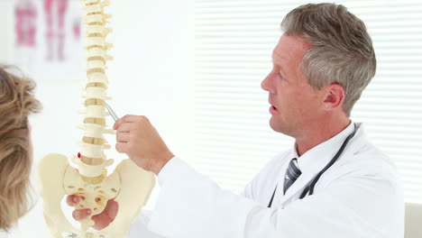 -Physiotherapist-explaining-spine-model-to-patient