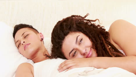 Smiling-lesbian-couple-together-in-the-bed