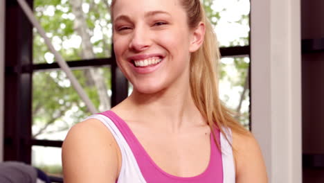 Fit-woman-smiling-to-camera-while-people-doing-some-stretching