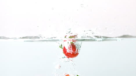 Strawberries-falling-in-water-on-white-background