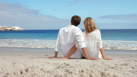 Happy-couple-sitting-on-the-beach