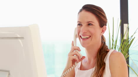 Lächelnde-Frau,-Die-Einen-Computer-Benutzt,-Während-Sie-Telefoniert
