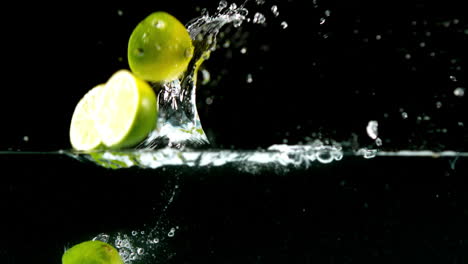 Limas-Cayendo-En-Agua-Sobre-Fondo-Negro.