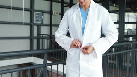 Smiling-doctor-buttoning-up-lab-coat