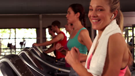 Fit-smiling-woman-running-on-treadmills-while-listening-music