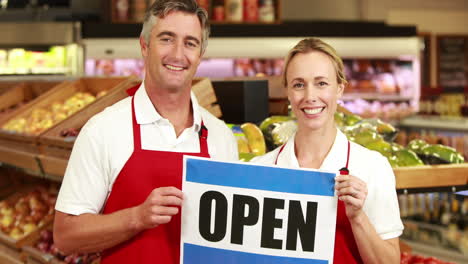 Smiling-workers-holding-open-sign