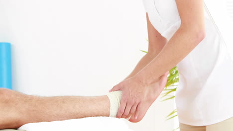 Physiotherapist-wrapping-injured-ankle-in-bandage