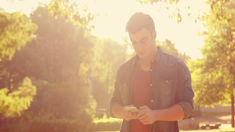 Handsome-man-using-his-smartphone-in-the-park