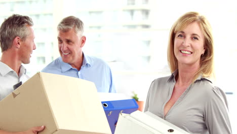 Business-people-holding-box-and-looking-at-camera