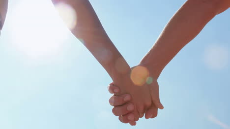 Close-up-of-couple-holding-hands-at-the-beach
