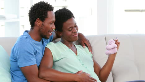 Pregnant-woman-showing-baby-shoes-on-the-sofa