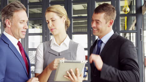 Business-people-talking-together-while-looking-tablet