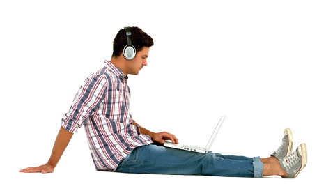 Hombre-Con-Auriculares-Sentado-En-El-Suelo-Usando-Una-Computadora-Portátil