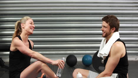 Smiling-fit-couple-sitting-on-mat-talking