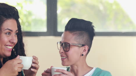 Smiling-lesbian-couple-drinking-coffee-together