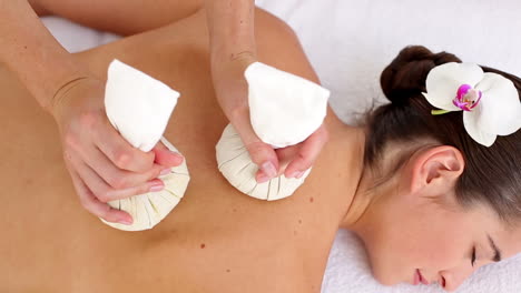 Woman-enjoying-a-herbal-compress-massage