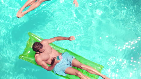 Attractive-couple-relaxing-on-lilos-in-pool