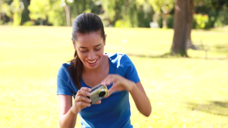 Smiling-brunette-taking-pictures-in-the-park