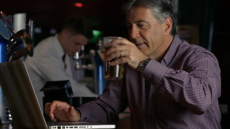 Mann-Trinkt-Ein-Bier-An-Der-Bar-Mit-Laptop