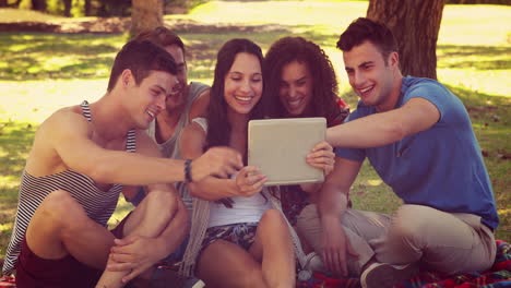 Happy-friends-using-tablet-in-the-park