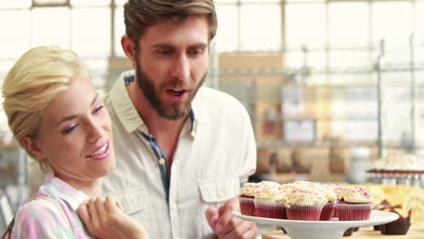 Happy-couple-pointing-cupcakes-at-restaurant-