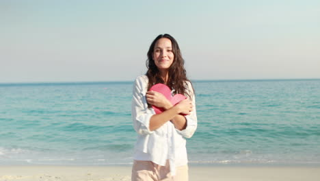Smiling-woman-holding-heart-card-at-the-beach