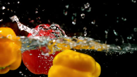 Peppers-falling-in-water-on-black-background