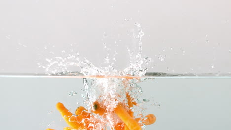 Carrots-falling-in-water-on-white-background