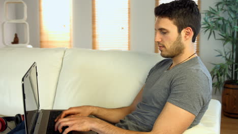 Hombre-Usando-Su-Computadora-Portátil-En-El-Sofá