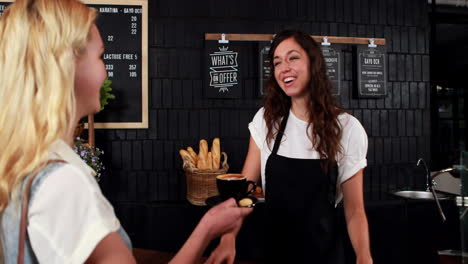 Smiling-waitress-offering-coffee-to-pretty-customer