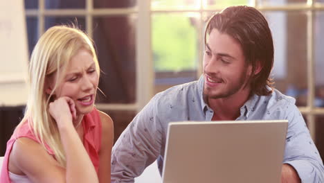 Smiling-casual-business-workers-using-laptop-together