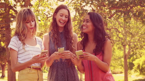 Happy-female-friends-using-their-smartphones-and-laughing