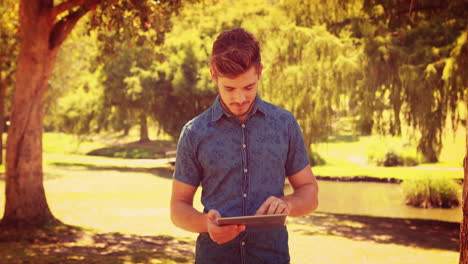 Handsome-man-using-tablet-in-the-park