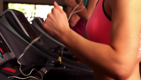 Fit-woman-running-on-treadmills-while-listening-music