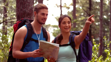 Couple-hiking-through-a-forest-looking-at-map