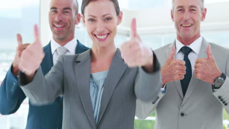 Business-people-looking-at-camera-with-thumbs-up-