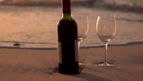 Botella-De-Vino-Tinto-Y-Copas-En-La-Arena-De-La-Playa.-