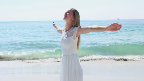 Happy-blonde-woman-with-arms-outstretched-at-the-beach