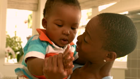 Mother-holding-baby-son-in-the-kitchen