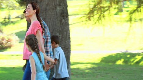 Familia-Feliz-Caminando-En-El-Parque