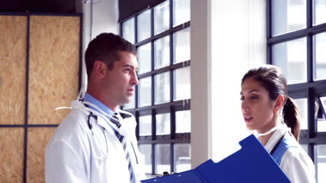 Doctors-speaking-together-while-writing-notes-on-clipboard