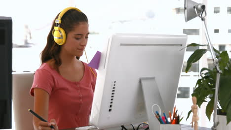 Casual-businesswoman-working-on-computer-and-listening-music