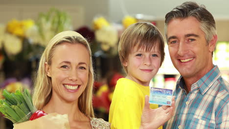 Smiling-family-with-paper-bag-showing-credit-card